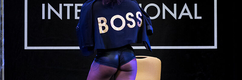 Pole Dancer Wears Jacket With The Word "Boss" Across The Back.