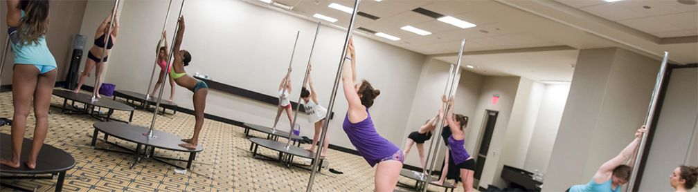 Students stretching on portable dance poles.