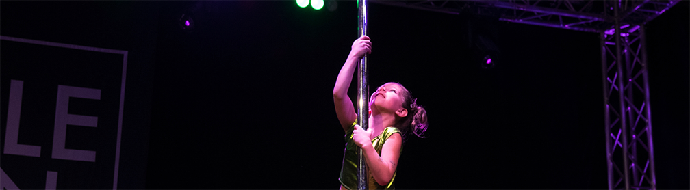 Child dancer climbing a pole on stage.
