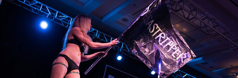 Performer On Stage Waves A Flag With Stripper Text On It.