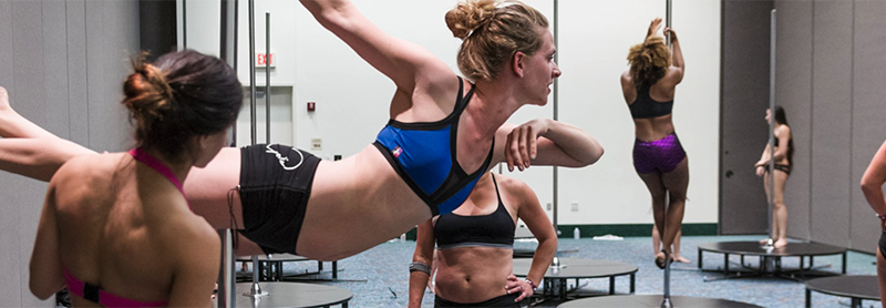 Students Watch An Instructor During A Pole Dance Workshop.