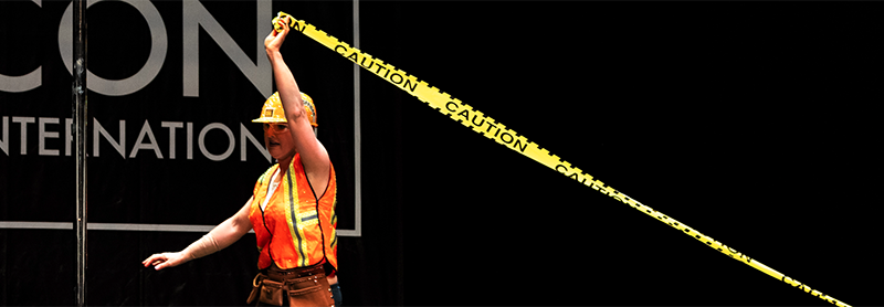 Pole Dancer In Hard Hat With Caution Tape Dances On Stage.