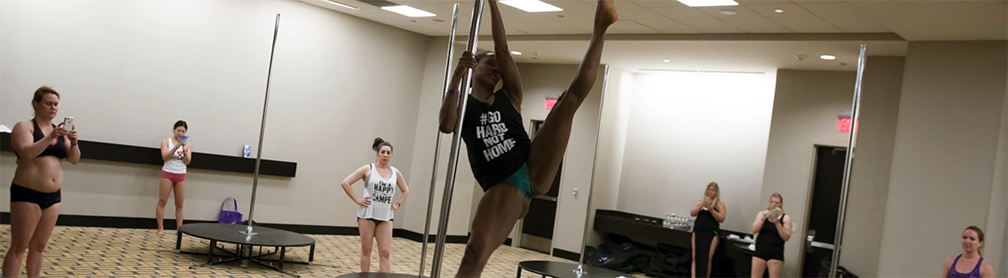 Pole Class, instructor demoing pole dance move.